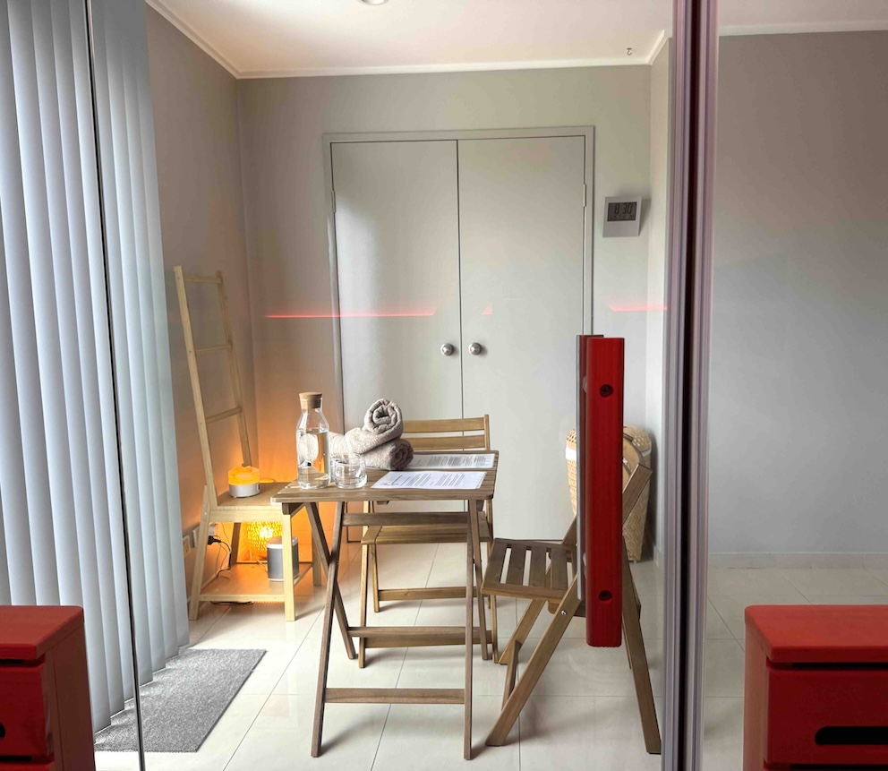 Small table and chairs set in a minimal room for TCM acupuncture, towels and water on the table.