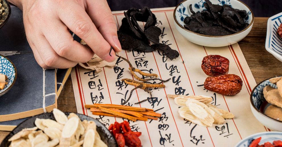 Hand arranging herbs on calligraphy paper, evoking dry needling for neck and shoulder pain.