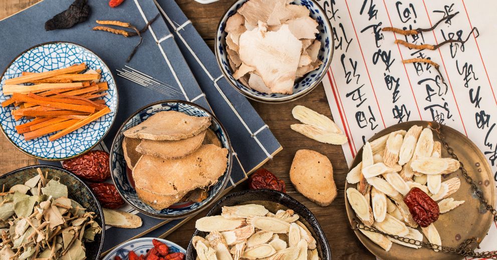 Bowls of dried herbs and roots highlight common misconceptions about TCM beside Chinese texts.