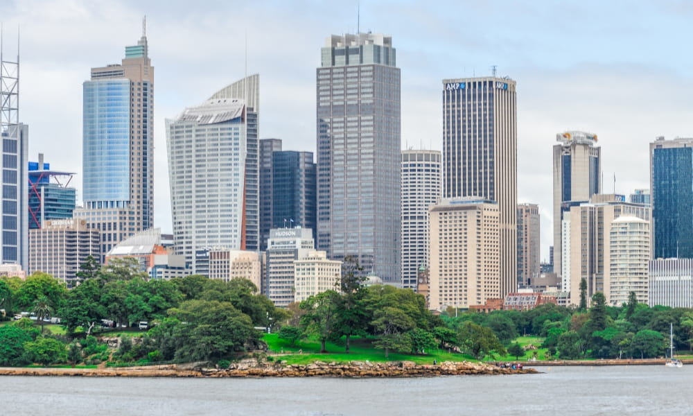 City skyline with modern skyscrapers, a waterfront park, and Acupuncture Surry Hills nearby.